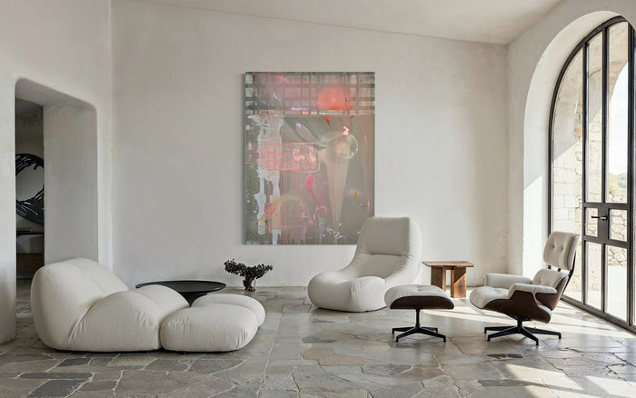 Large abstract painting by Artemis Orttu in a white stone room with a white sofa, lounge chair and arched window