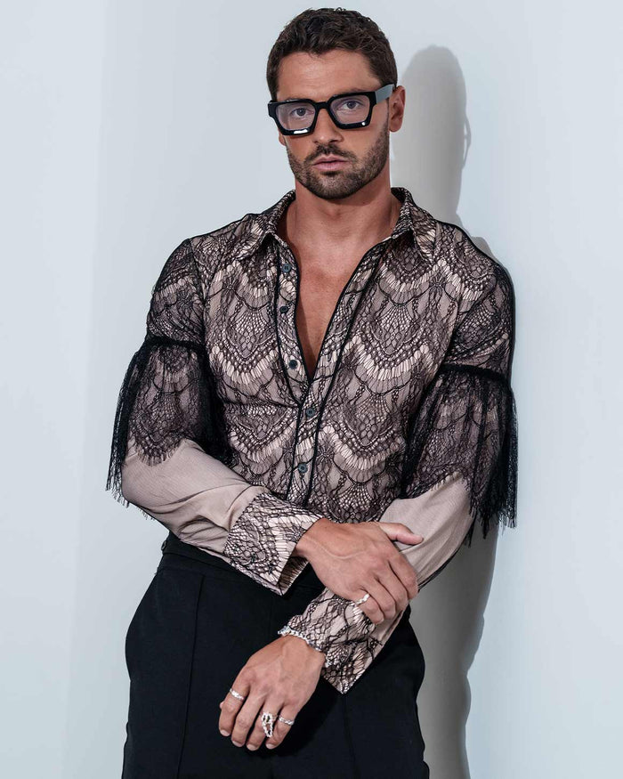 Man wearing a patterned shirt with sheer sleeves against a white background