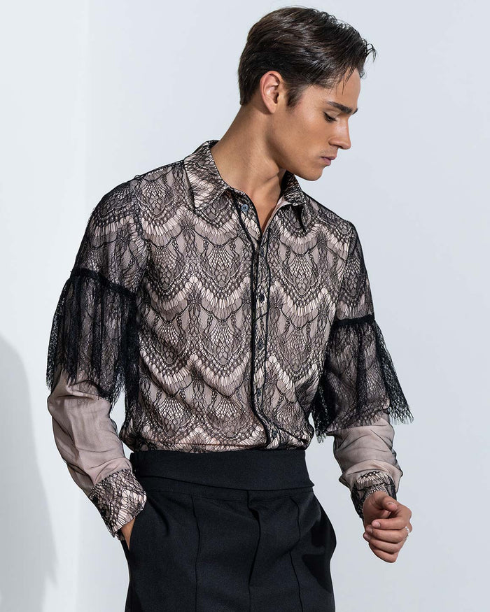 Man wearing a sheer lace shirt with a plain background